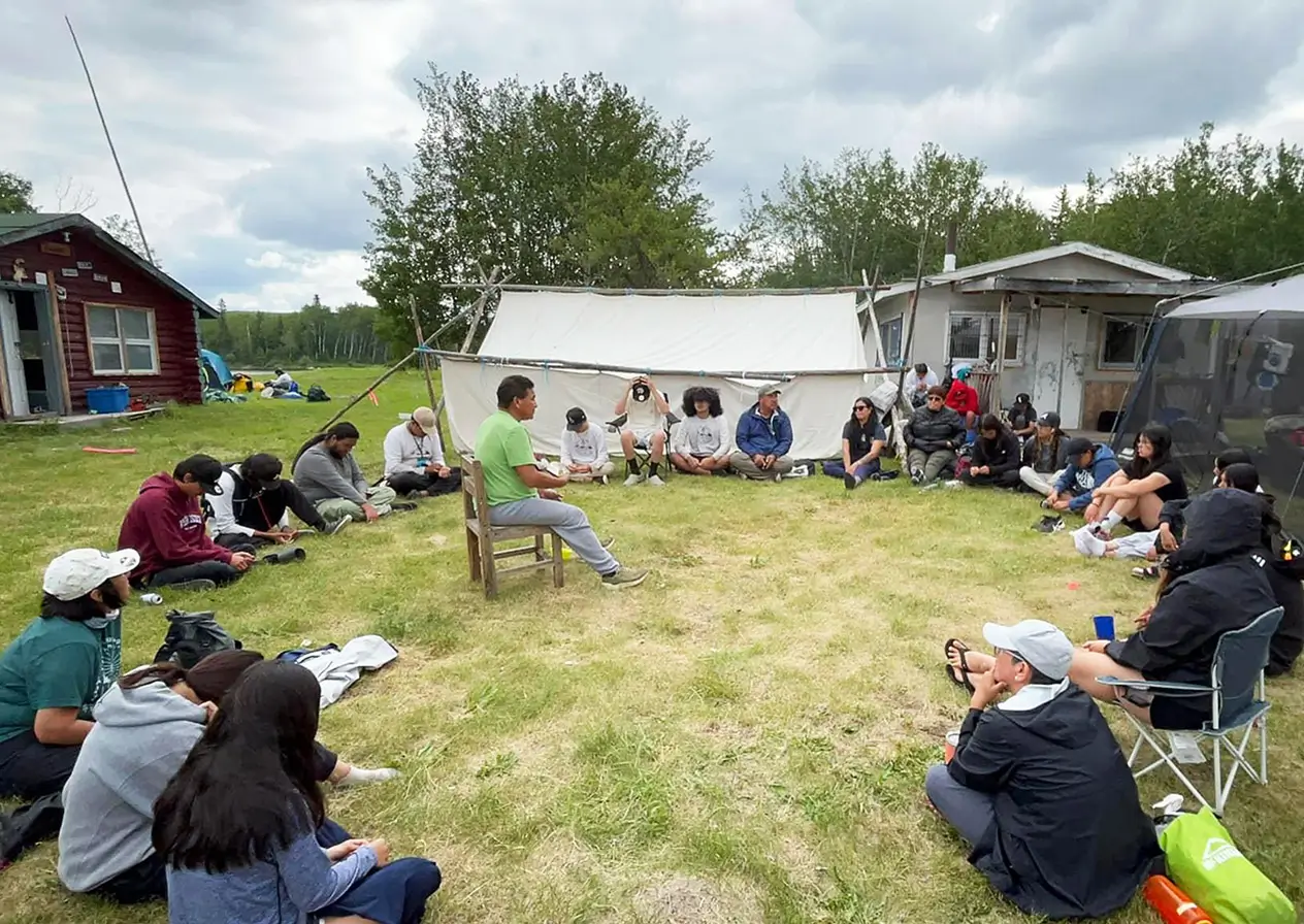 students sitting in a circle listening to a leader