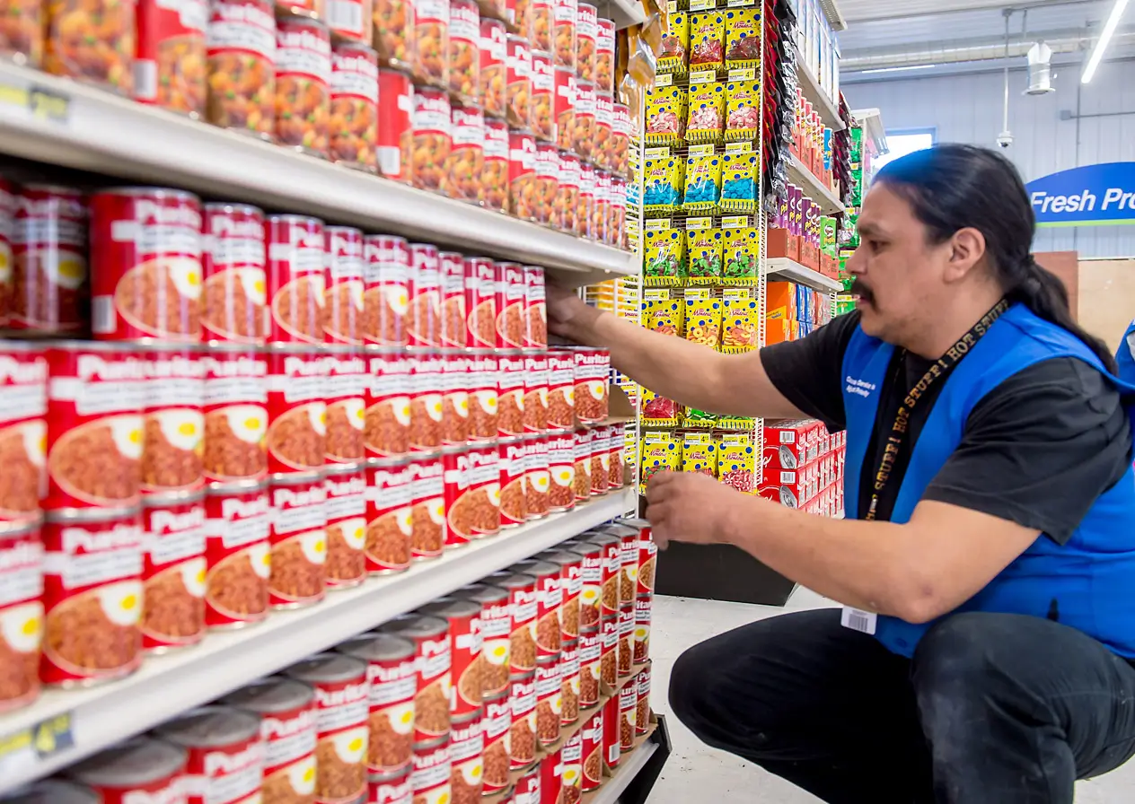 employee of Northern Stores with dark hair in a ponytail and a mustache stacking shelves