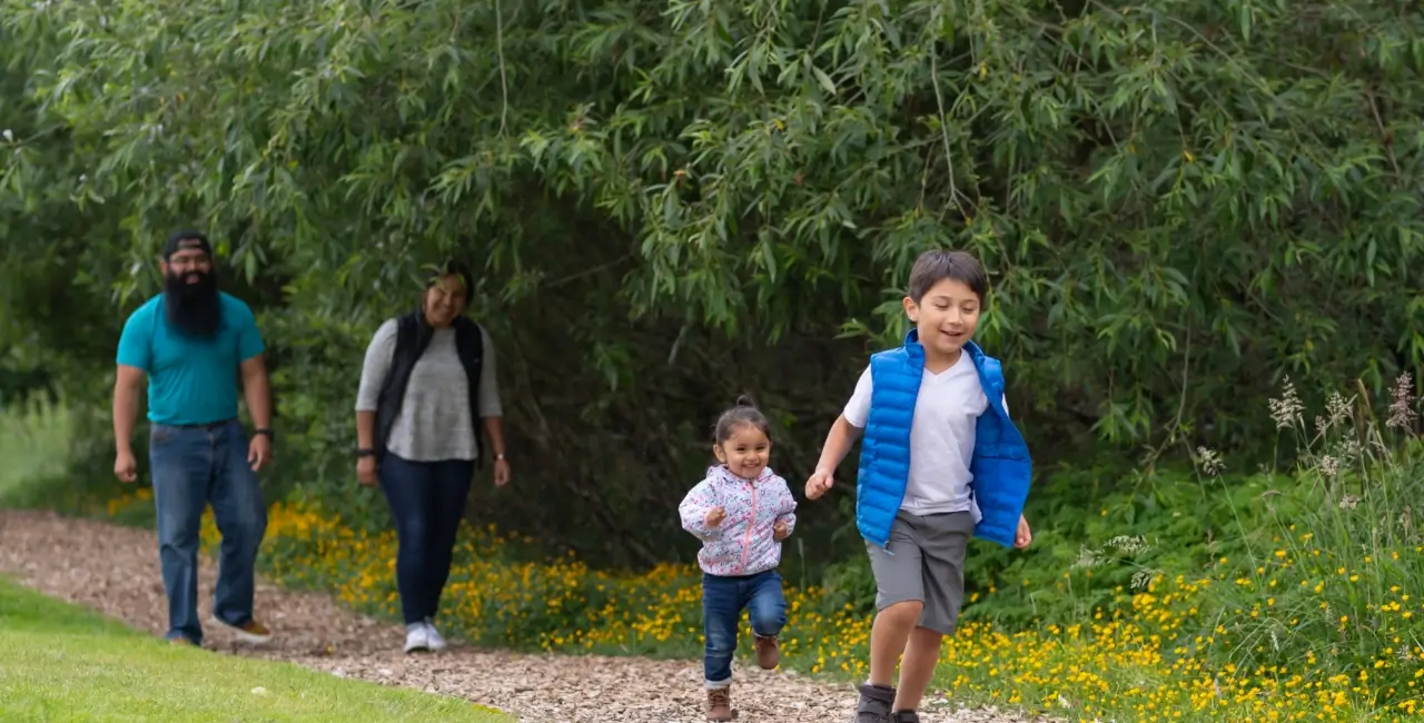 mother and father with young daughter and son running down a path