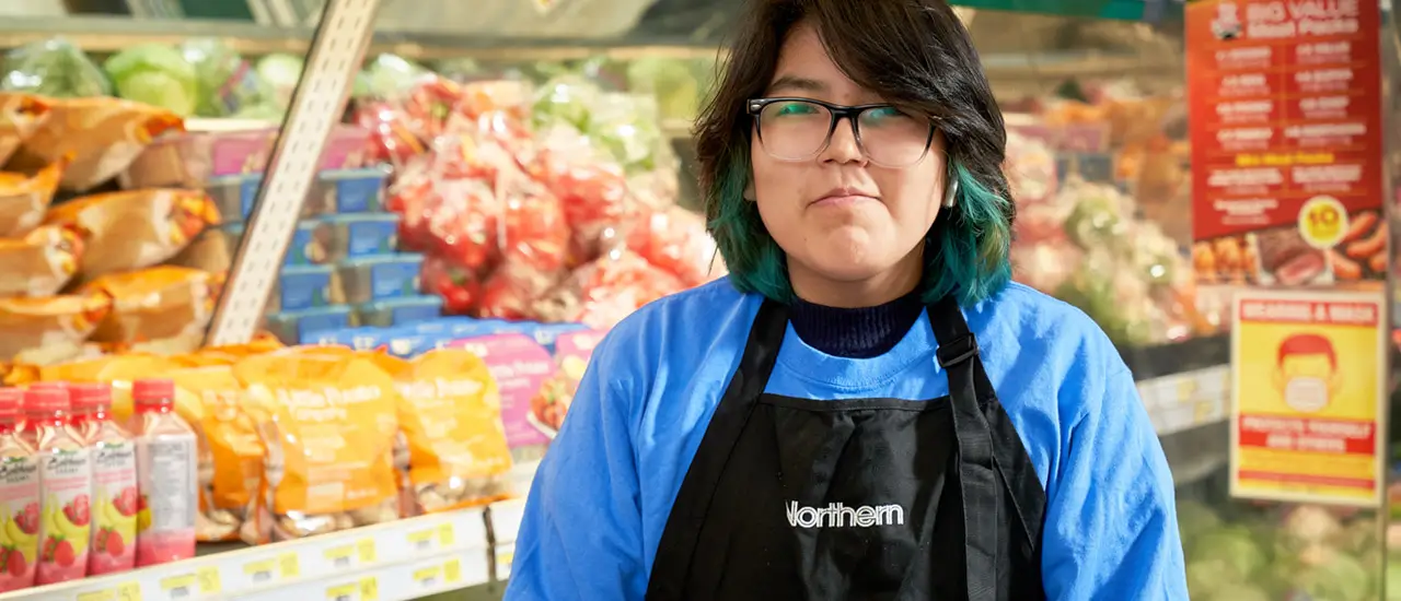 A young girl with glasses stands in front of the produce counter. Ask her anything about the produce.
